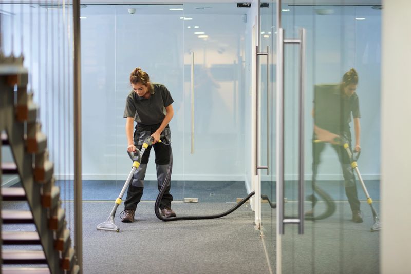 a female cleaning contractor is  steam cleaning an office carpet in a empty office in between tenants.  .