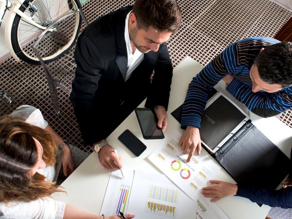 Three people analyzing charts and data at a table.