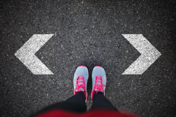 Person standing at a crossroads with arrows pointing left and right.
