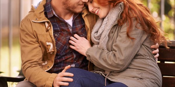 Couple sharing a tender moment on a bench.