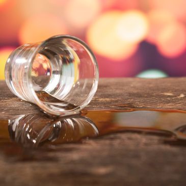 Spilled drink from a tipped glass on a wooden surface.