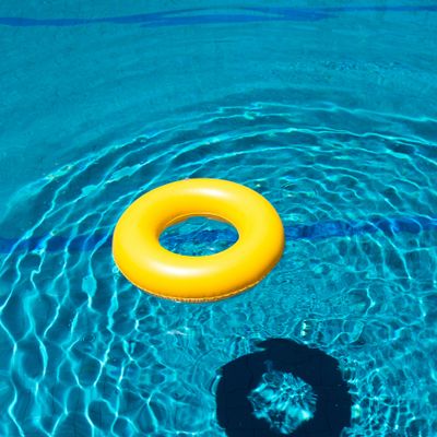 A bright yellow inflatable ring floating in a clear blue swimming pool.