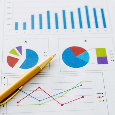 Close-up of business charts and a gold pen on paper.