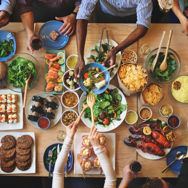 Friends sharing a diverse and colorful meal around a wooden table.