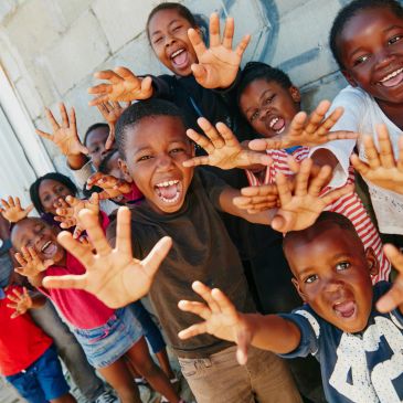 Niños alegres con manos extendidas mirando a la cámara.