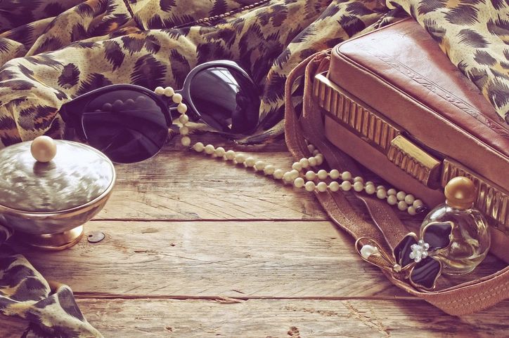 womens vintage accessories, powder box, scarf, necklace, sunglasses and handbag on wooden table