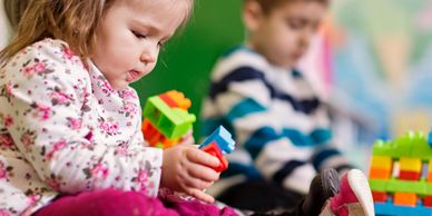 Young children focused on building with colorful toy blocks indoors.