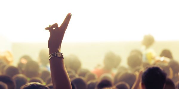 A raised hand in a crowd at a bright event.