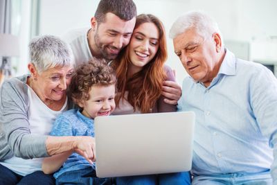 A happy multi-generation family looking at a laptop together.