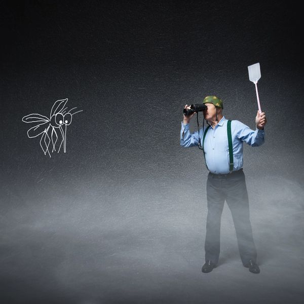 Man in helmet with binoculars and fly swatter faces giant cartoon mosquito.