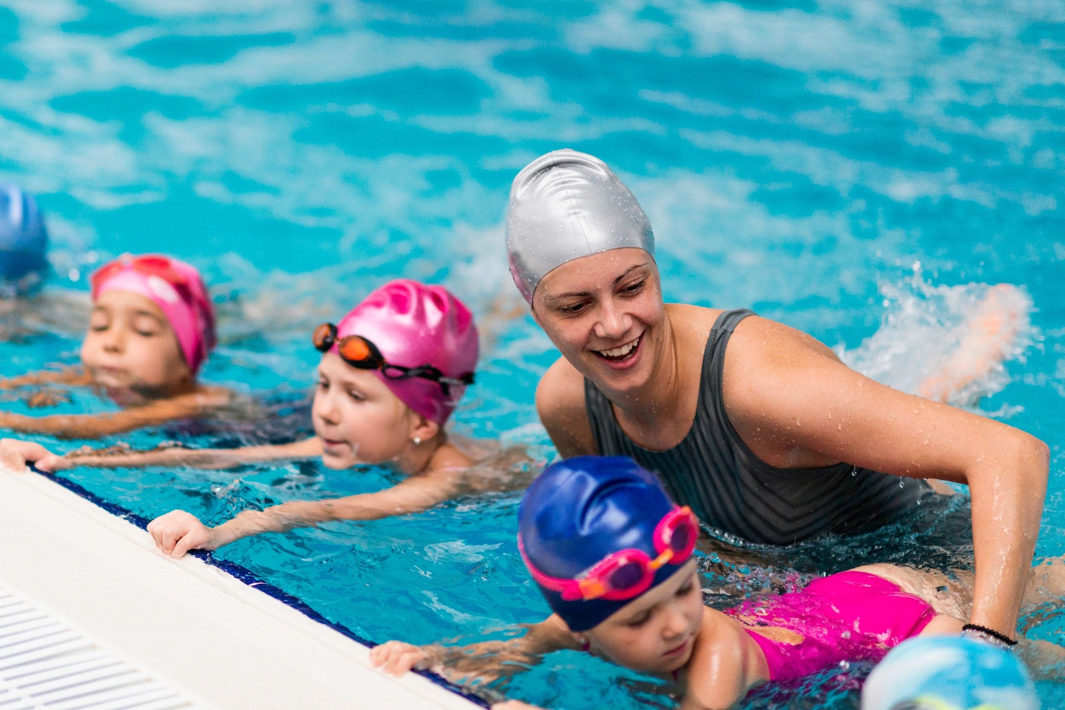 Swimming instructor teaching children in a pool.