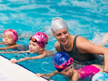 Swimming instructor teaches young children in a pool.