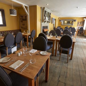 Cozy, empty restaurant with wooden floors and yellow walls.