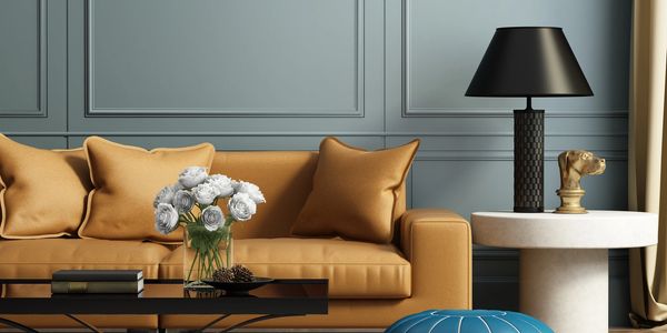 Modern living room with mustard sofa, black lamp, and white flowers.