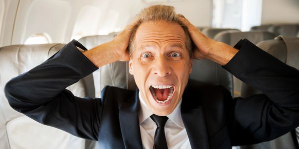 Man in suit screaming on plane.