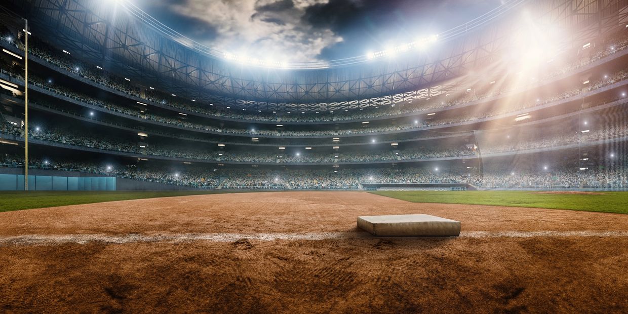 A brightly lit baseball stadium with a view of the field and base.