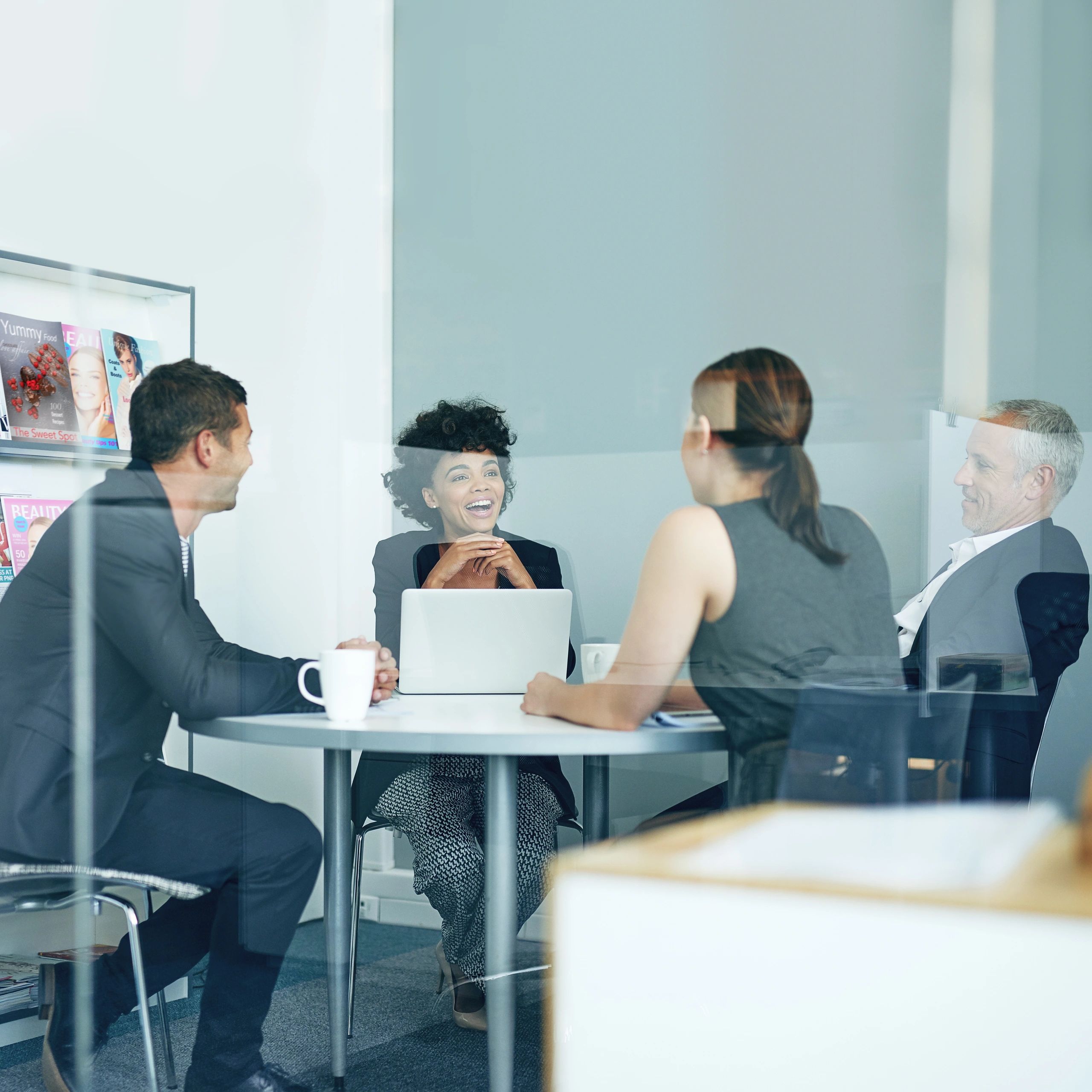 Colleagues smiling in a meeting through glass.