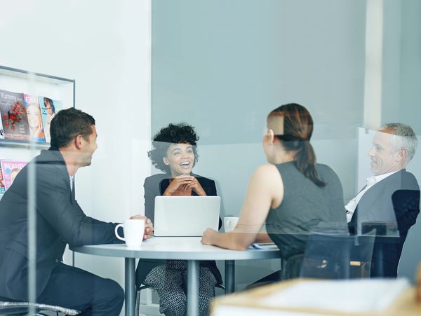 Four professionals engaged in a lively meeting around a conference table.