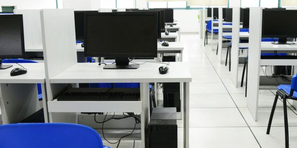 Empty computer lab with rows of desks and monitors.