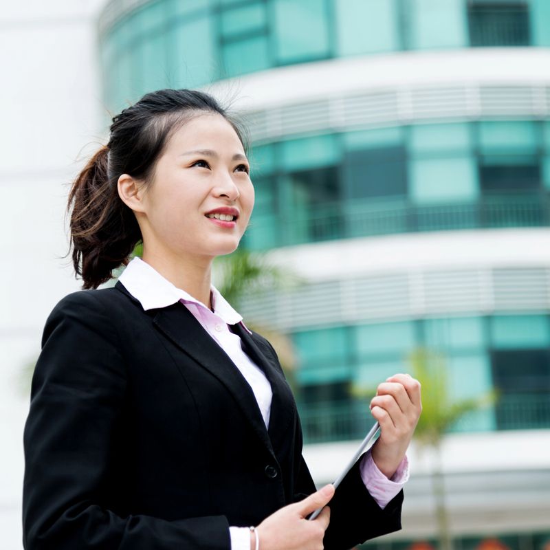 Attractive asian businesswoman using digital tablet outside offic building.