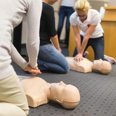People practicing CPR on training mannequins in a class.