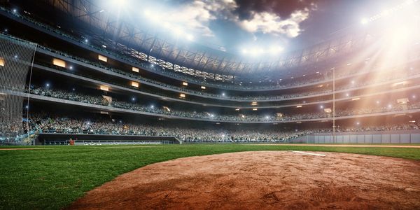 A brightly lit, packed baseball stadium with a clear view of the pitcher's mound.