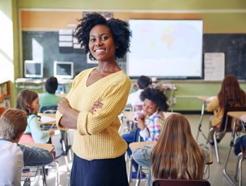 Confident teacher standing in front of her classroom full of students.