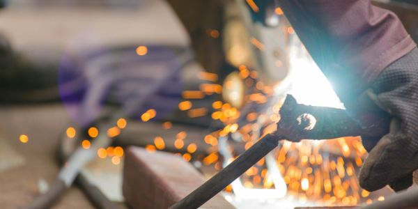 Close-up of a worker welding metal with sparks flying.
