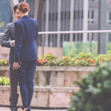 Two businesspeople conversing outdoors in formal attire.
