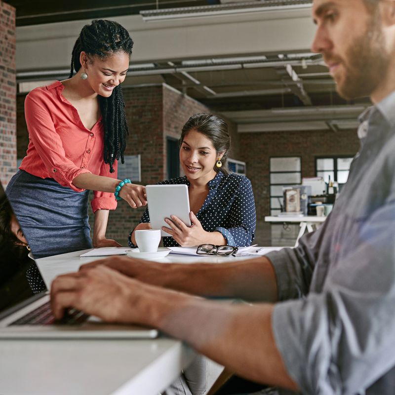 Shot of colleagues using a digital tablet together in a modern office
