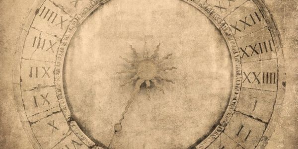Ancient clock face with Roman numerals and a sun motif in the center.