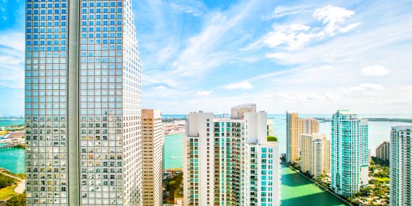 Sunny cityscape with tall buildings and water channels.
