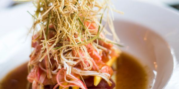 Gourmet dish with thinly sliced meat and crispy garnish in a flavorful broth.