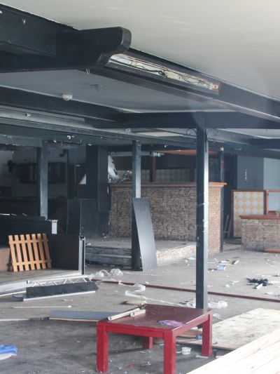 Abandoned, cluttered indoor space with scattered debris and furniture.
