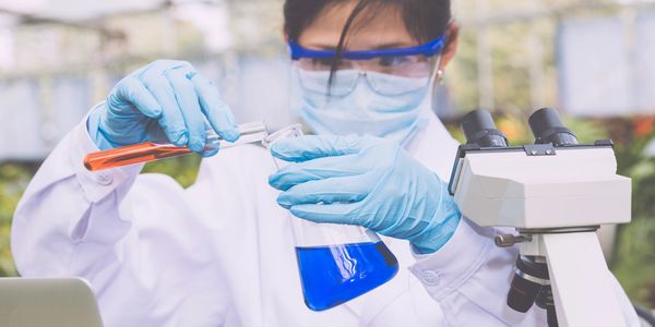 Scientist handling blue liquid with lab equipment.