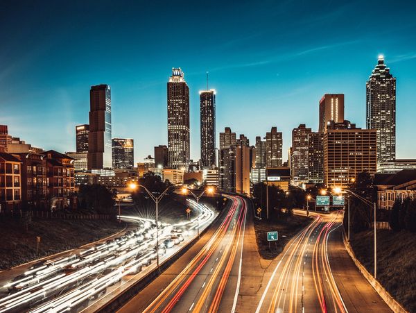 Nighttime city skyline with light trails on the highway.