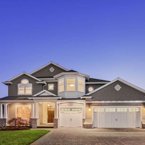 Elegant two-story house with warm lighting at dusk.