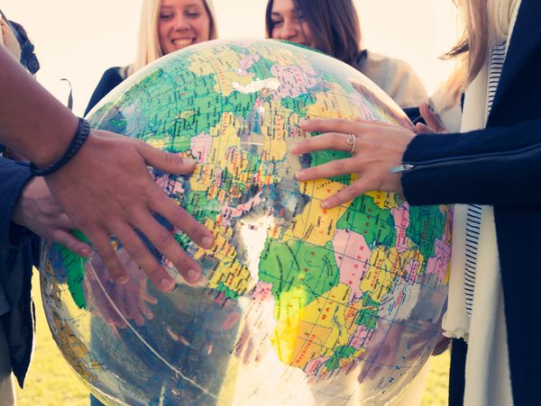 People holding a large globe, smiling and exploring geography together.
