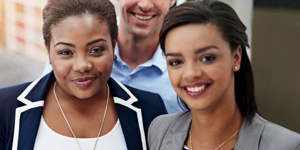 Three smiling professionals posing together in business attire.