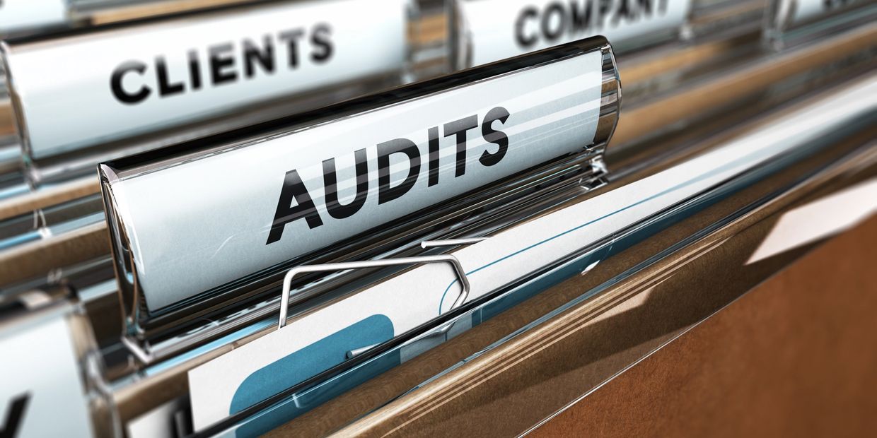 Close-up of audit files in a filing cabinet labeled 'AUDITS'.