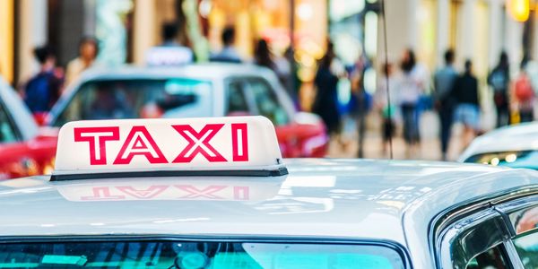 Taxi sign on top of a car in a busy street.
