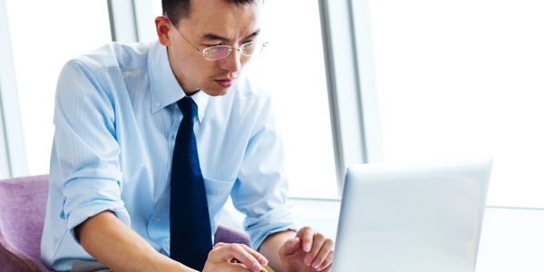 Focused man working on a laptop in a bright office.