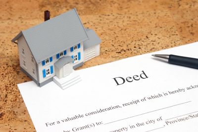 Miniature house model and deed document on a table.