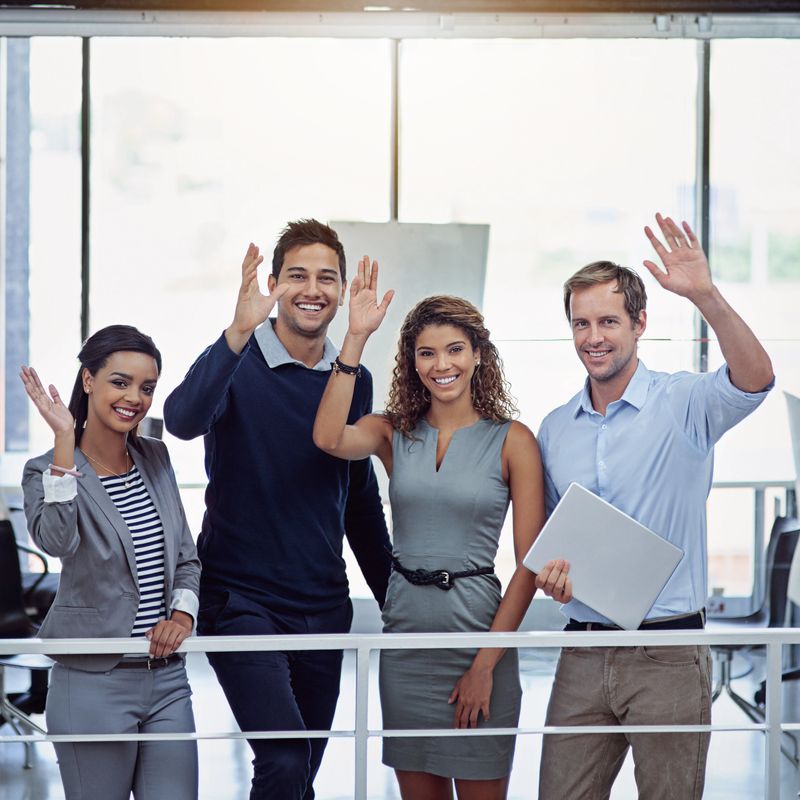 Portrait of a group of colleagues waving together in an office