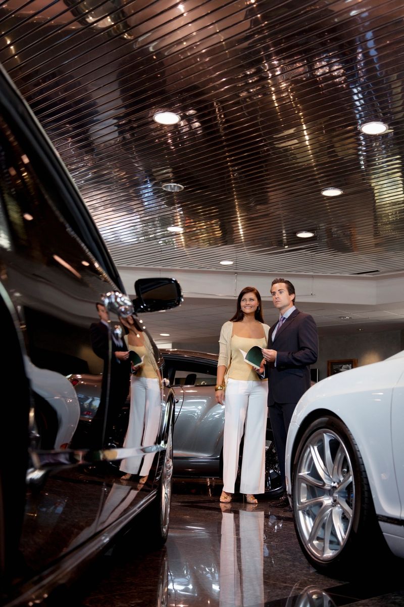 Woman standing with auto salesman in showroom