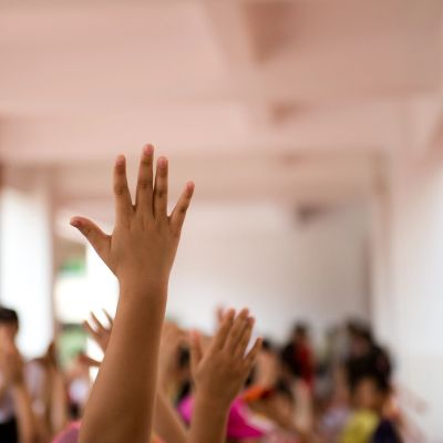 Raised hands in a classroom setting.