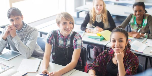 Group of diverse students smiling in a classroom.