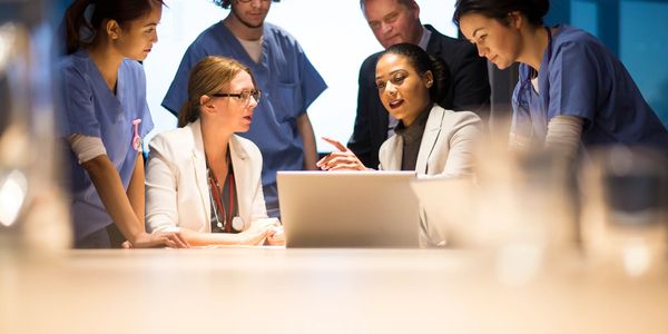 Medical team discussing patient care around a laptop.