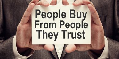 Hands showing a sign that says People Buy From People They Trust