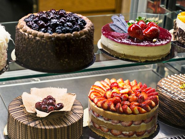 Variety of beautifully decorated cakes with fresh fruits in a display case.